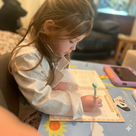 Child writing in a notebook with a pen at a table.
5-star verified review - 5-year-old girl learning to write numbers using TinkerMindz magic practice copybooks