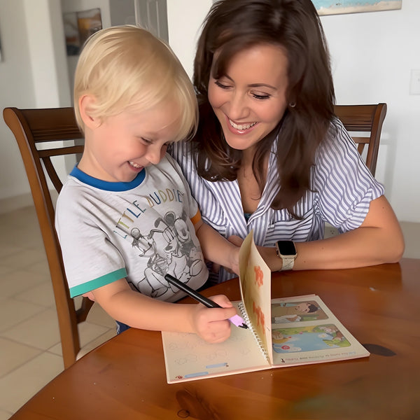 Mother helping young boy practice handwriting with TinkerMindz reusable magic copybook and ergonomic pen at kitchen table